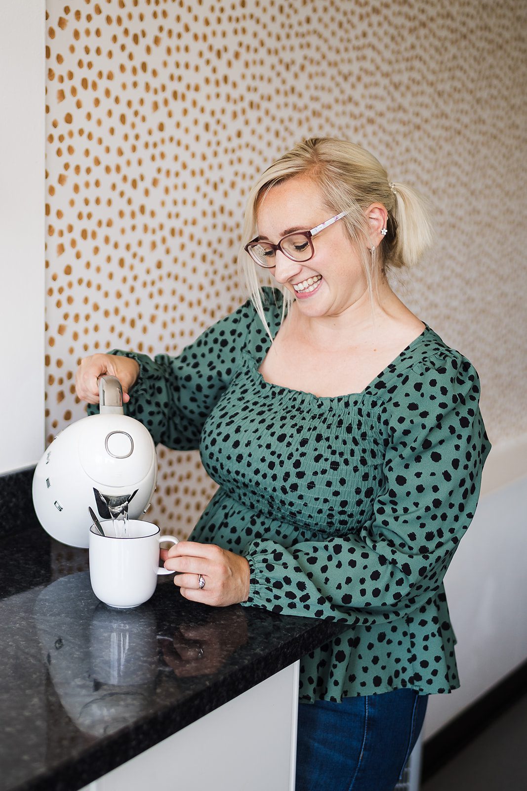 Katie pours from a kettle into a cup.