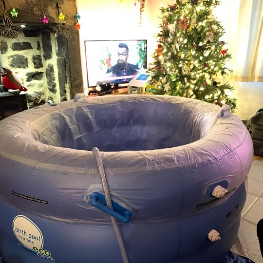 A blow up birth pool in a living room with a Christmas tree.